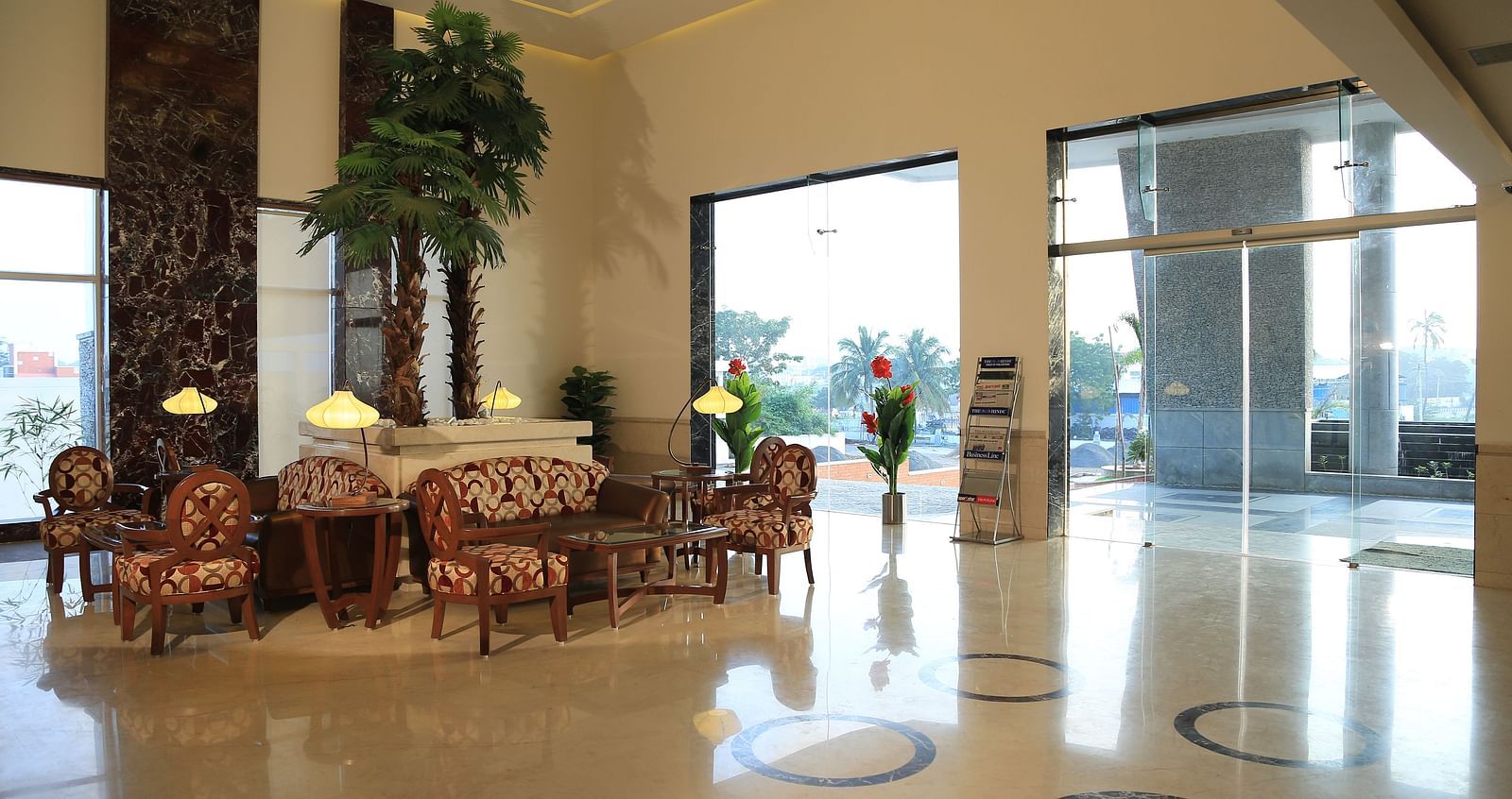 A spacious and elegant hotel lobby with natural lighting, cosy seating, and a welcoming reception area.- Dhanalakshmi Srinivasan Hotels, Perambalur