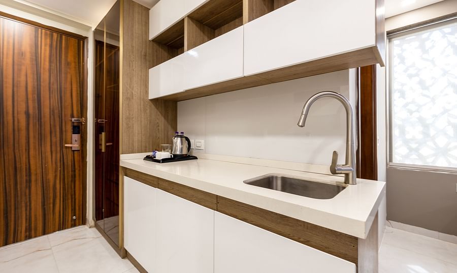 Modern kitchenette with sleek cabinets, a sink, and ample storage at Hotel Bawa, Gurgaon.