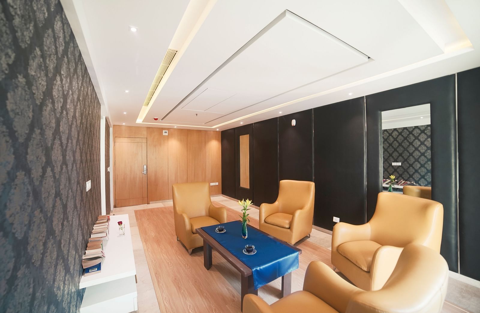 A spacious and inviting lounge area at BNGV Grandeur Hotel and Banquets, with light-colored upholstered chairs, a coffee table, and warm lighting.