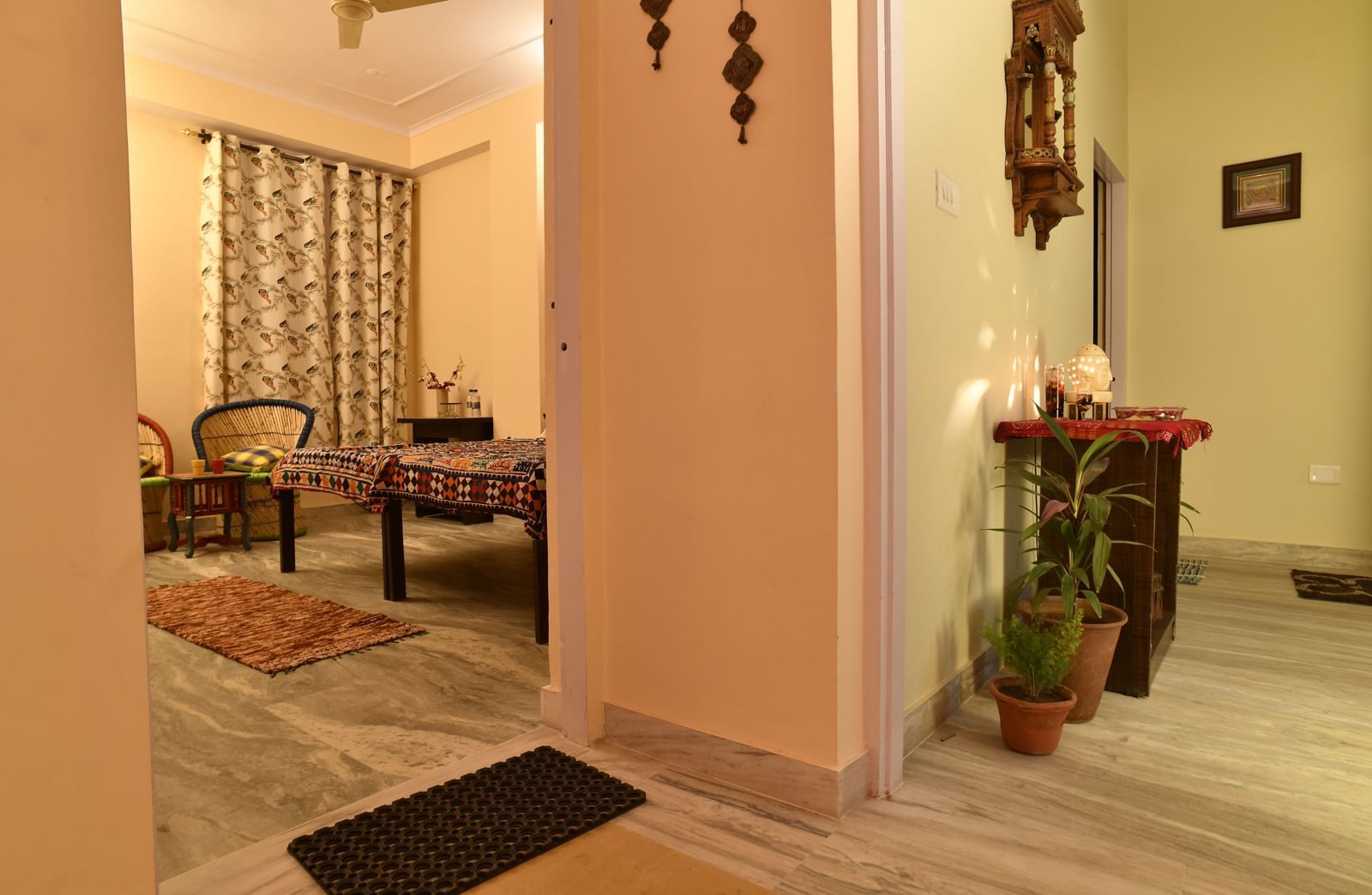 A hallway with potted plants, a dining table with chairs, and an adjoining room entrance at Jaypore360 Homestay in Jaipur.