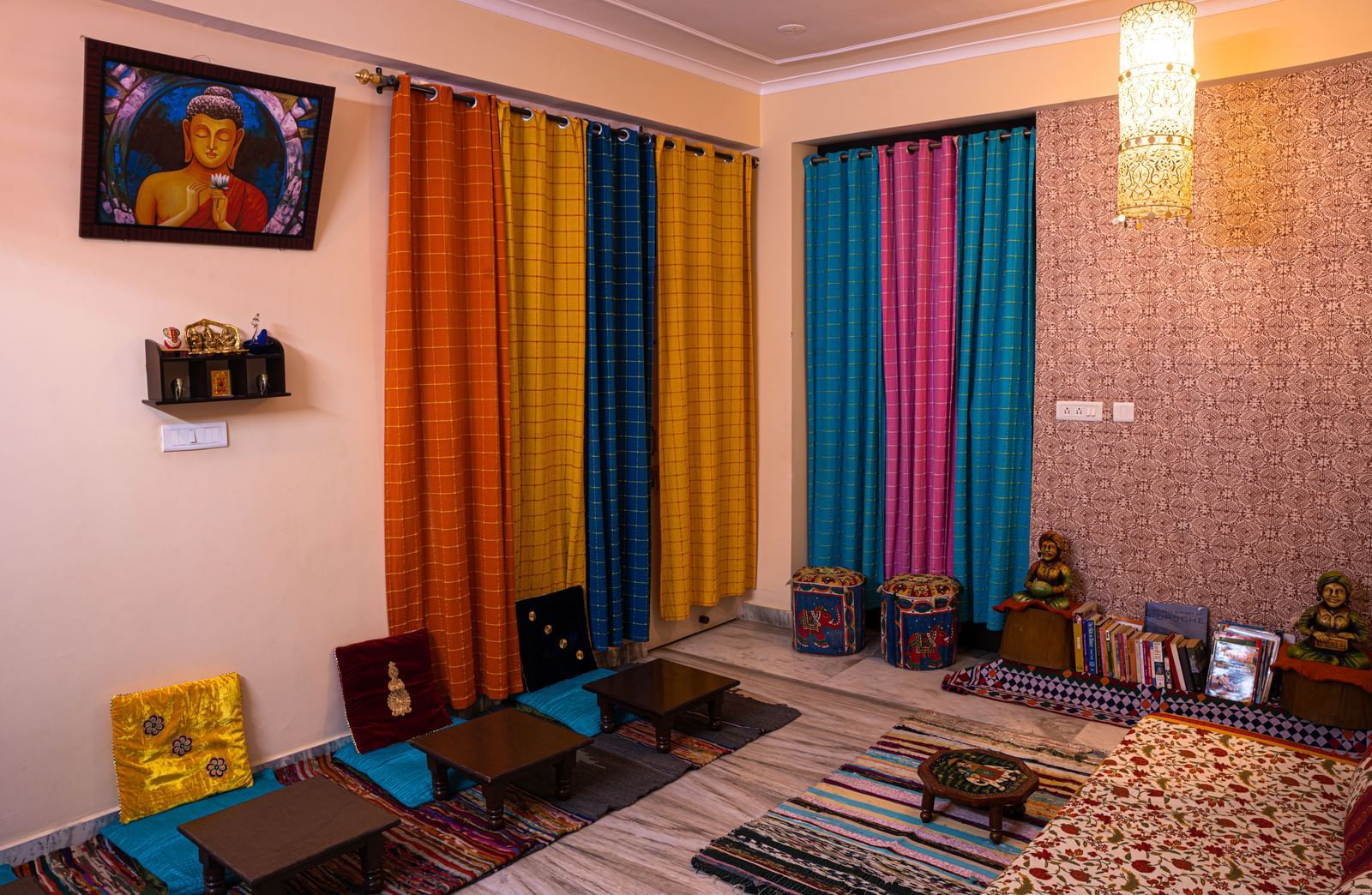 Floor seating with low tables, cushions, wall shelves, and draped curtains in a living space at Jaypore360 Homestay in Jaipur.