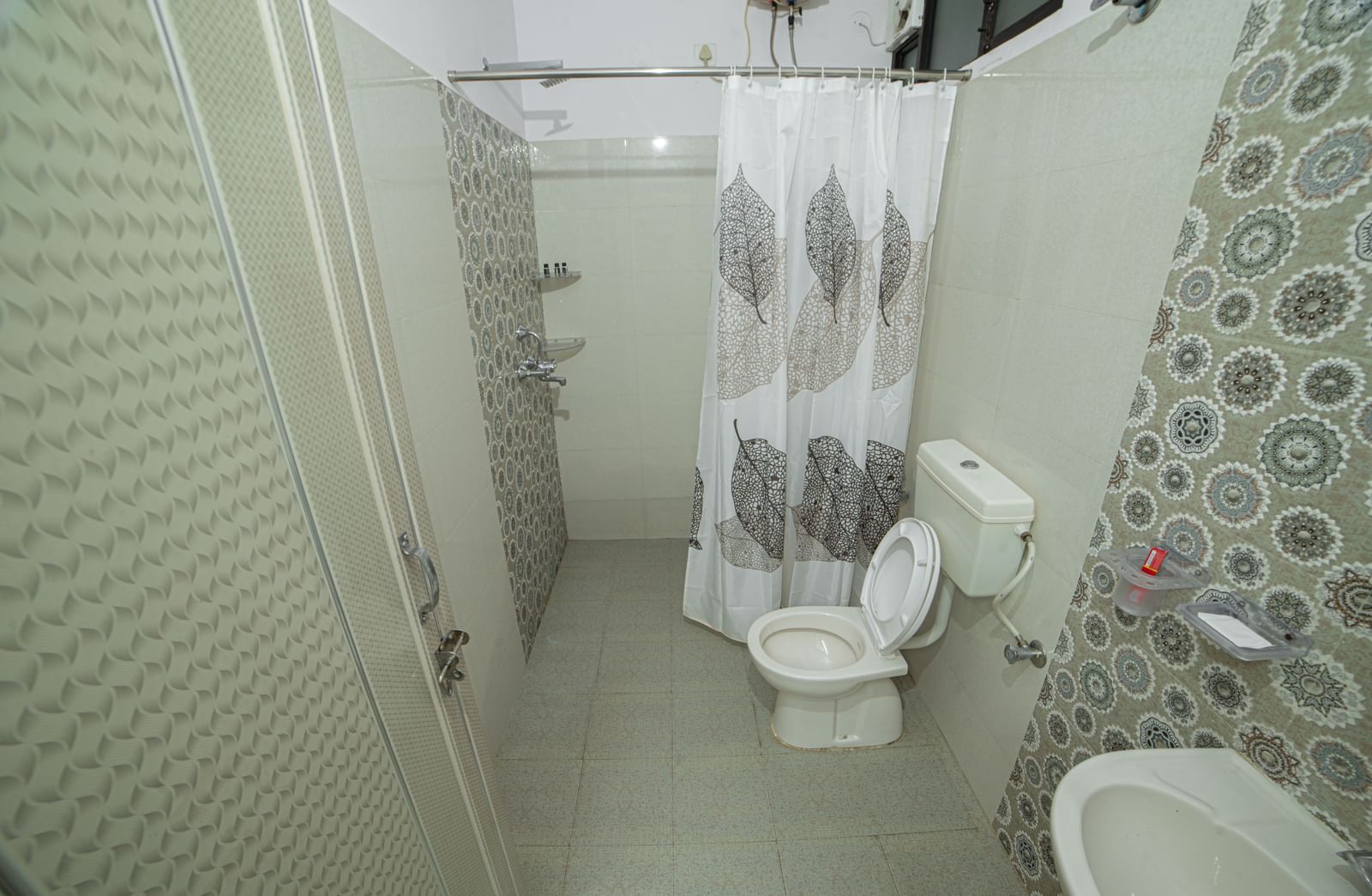 A bathroom with tiled walls, shower, toilet, bucket and shower curtain in view at Jaypore360 Homestay in Jaipur.