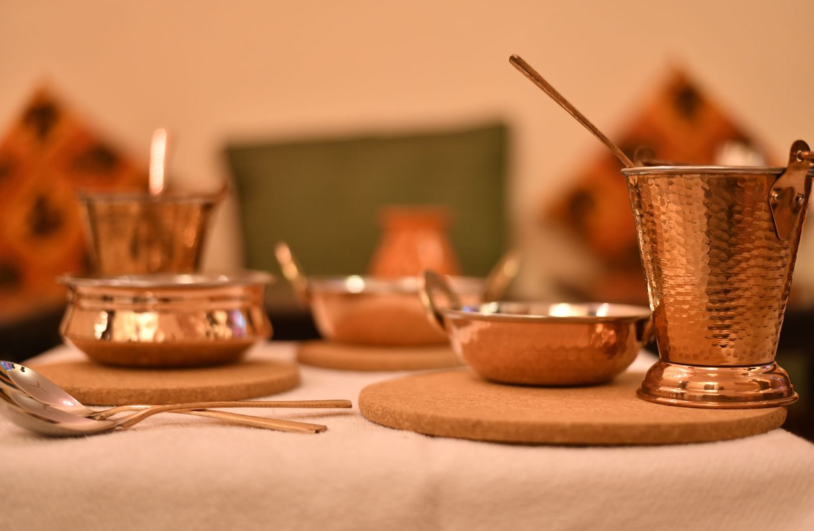 A close-up of traditional dining utensils including cups, plates, and ladles on a set dining table at Jaypore360 Homestay in Jaipur.
