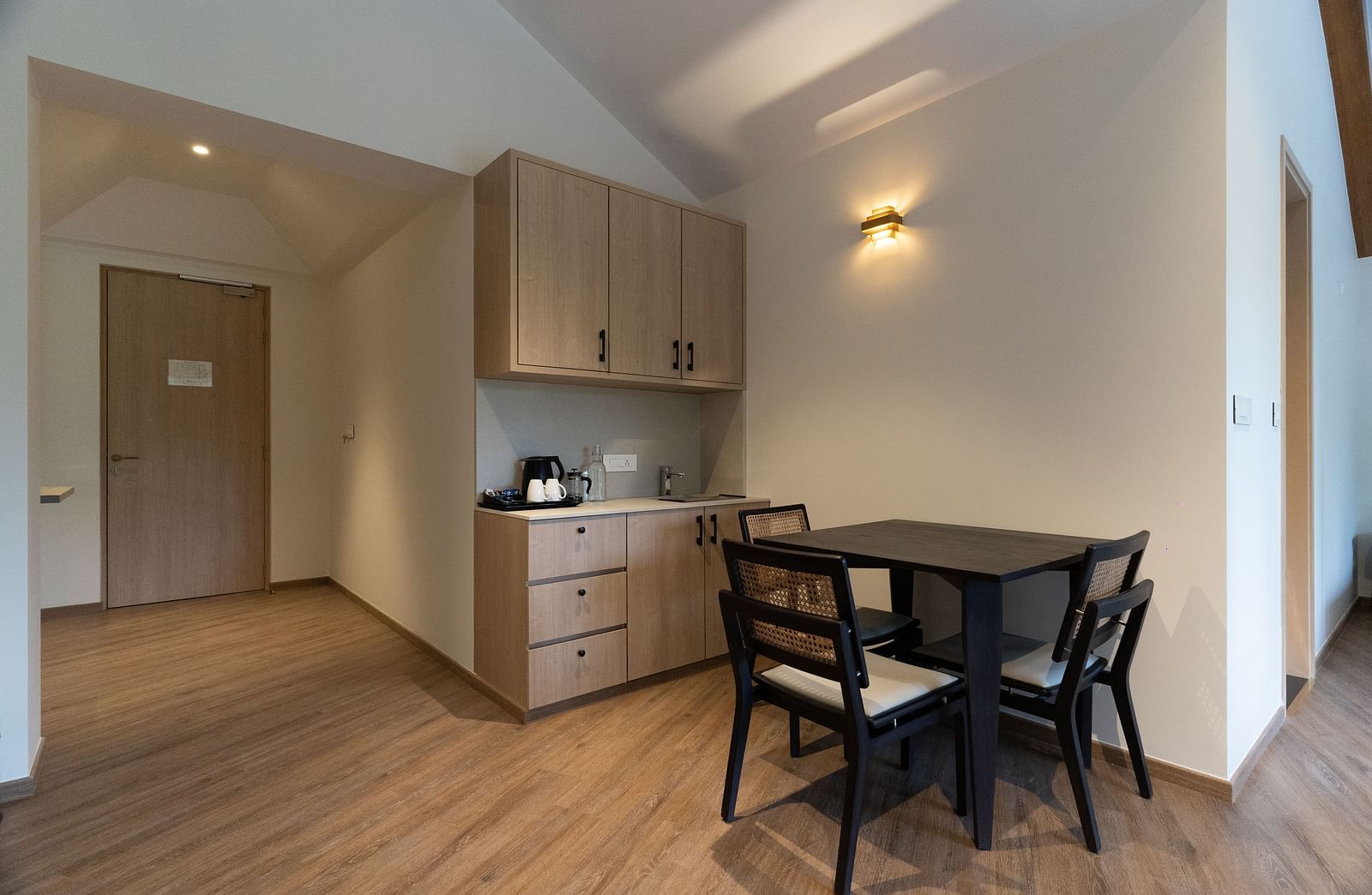 Cosy dining nook with table and chairs beside a wall-mounted wooden cupboard at Nivasana Manali.