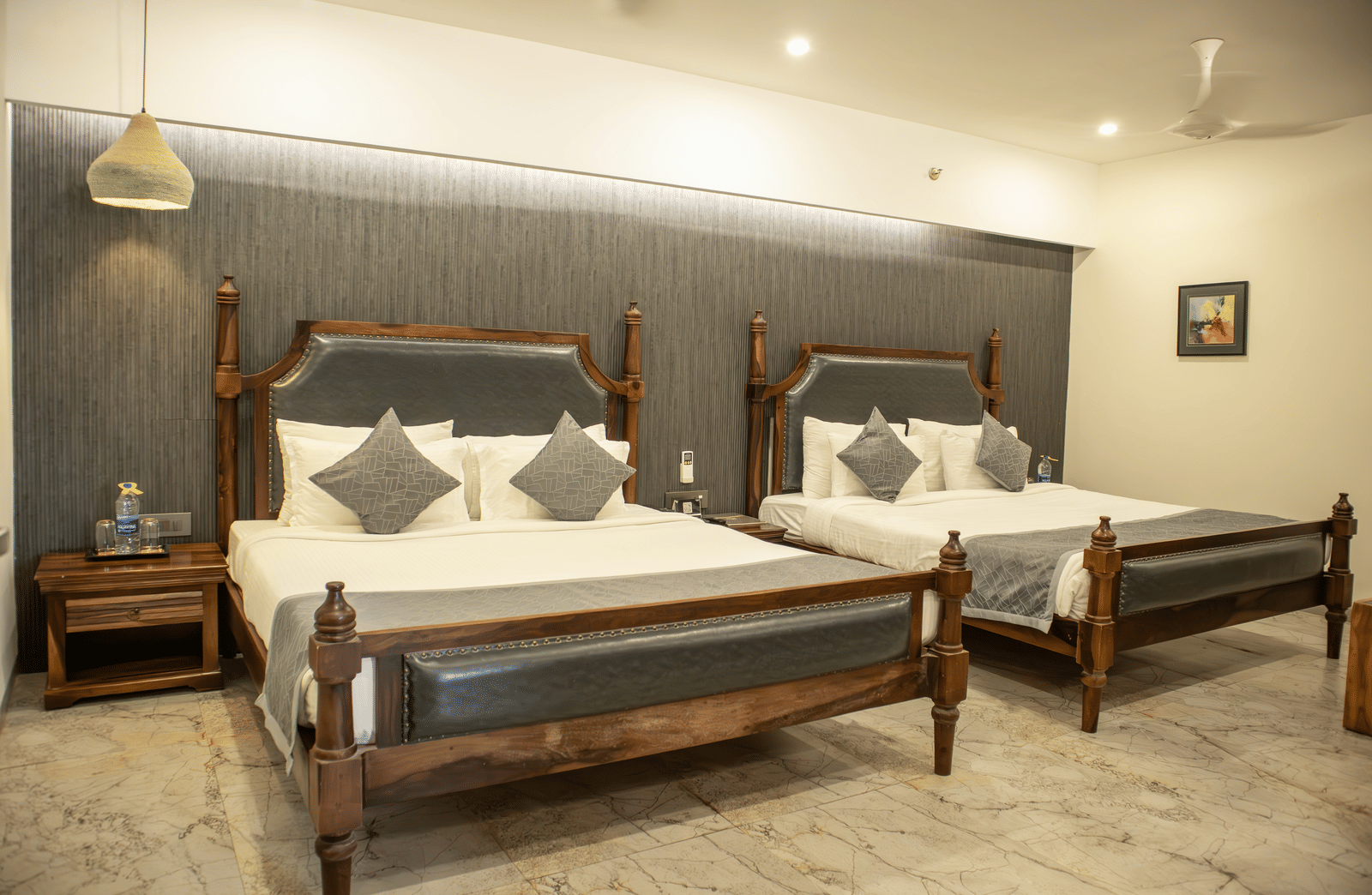 A bedroom setting having modern furnishing with twin beds, side tables, and bright lighting at Club Room of Papaya Tree Hotels.