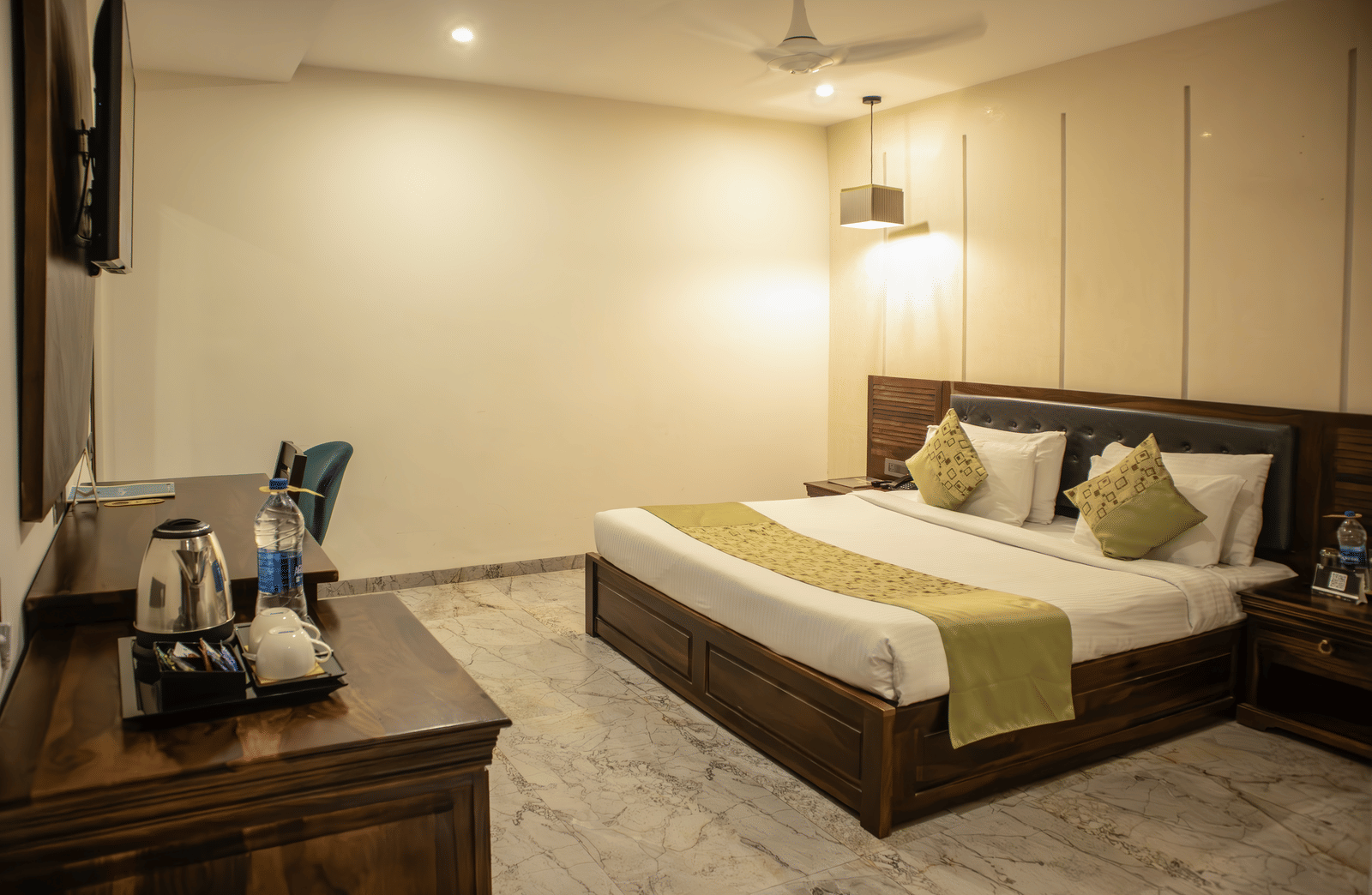 Executive Room of Papaya Tree Hotels with a double bed, an overhead lamp, and simple furnishing with a wooden cabinet.