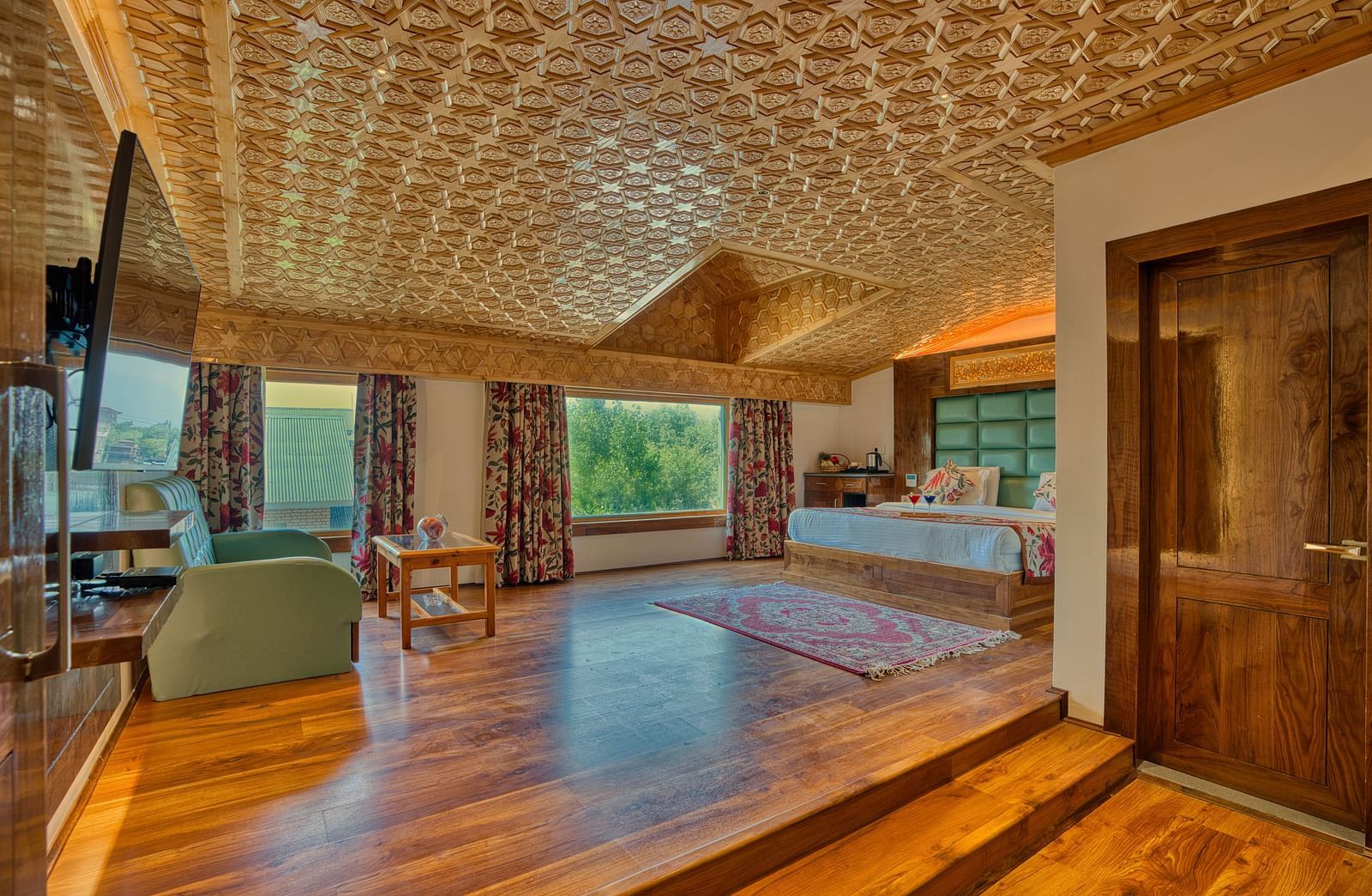 Spacious suite with elegant wooden floors and carved ceiling at Royal Comfort Regency, offering comfort with timeless charm.
