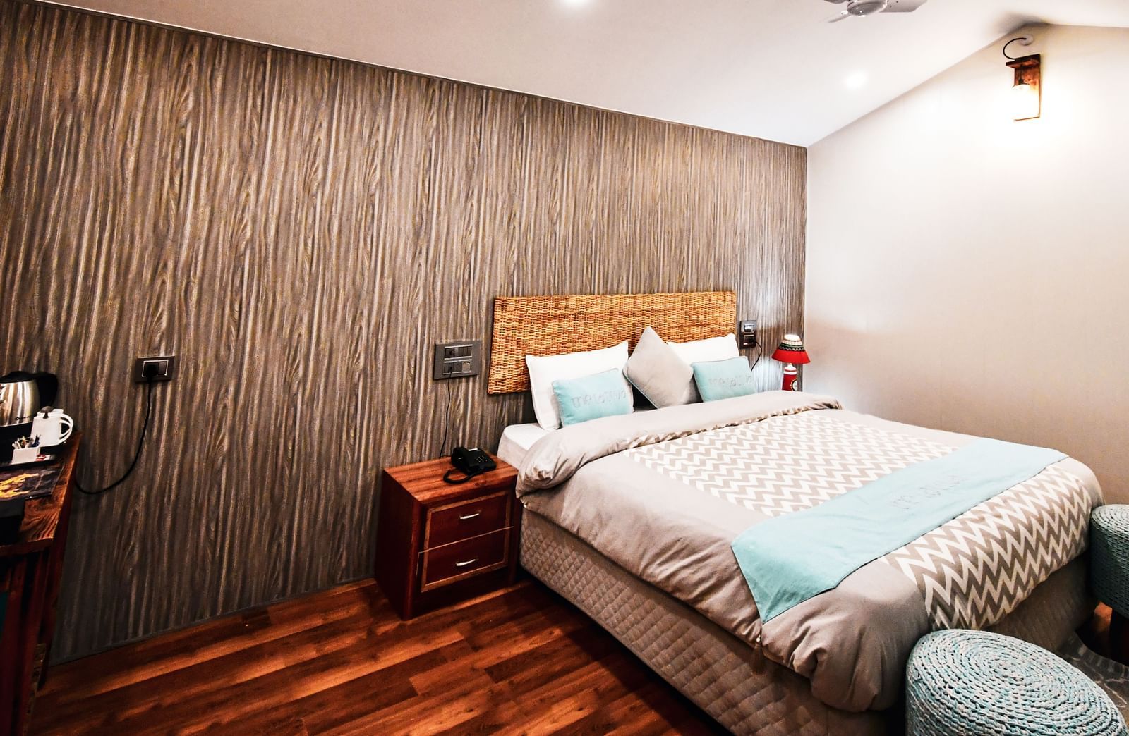 A standard room featuring a double bed in the corner with wooden flooring - The Tattva Boutique Resort