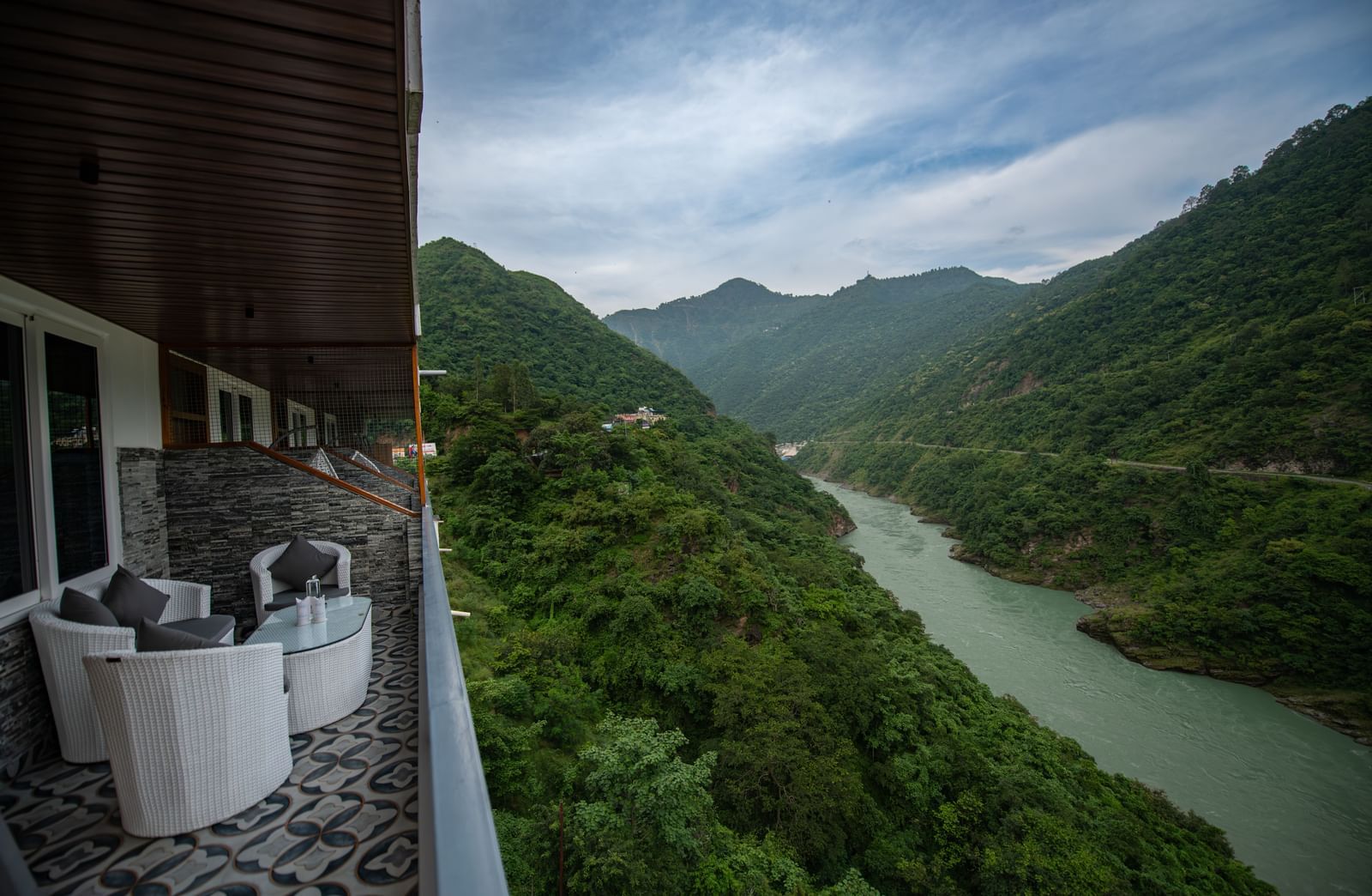 A balcony in the executive room at The Tattva Devaprayag with a view of the mountains and the river.
