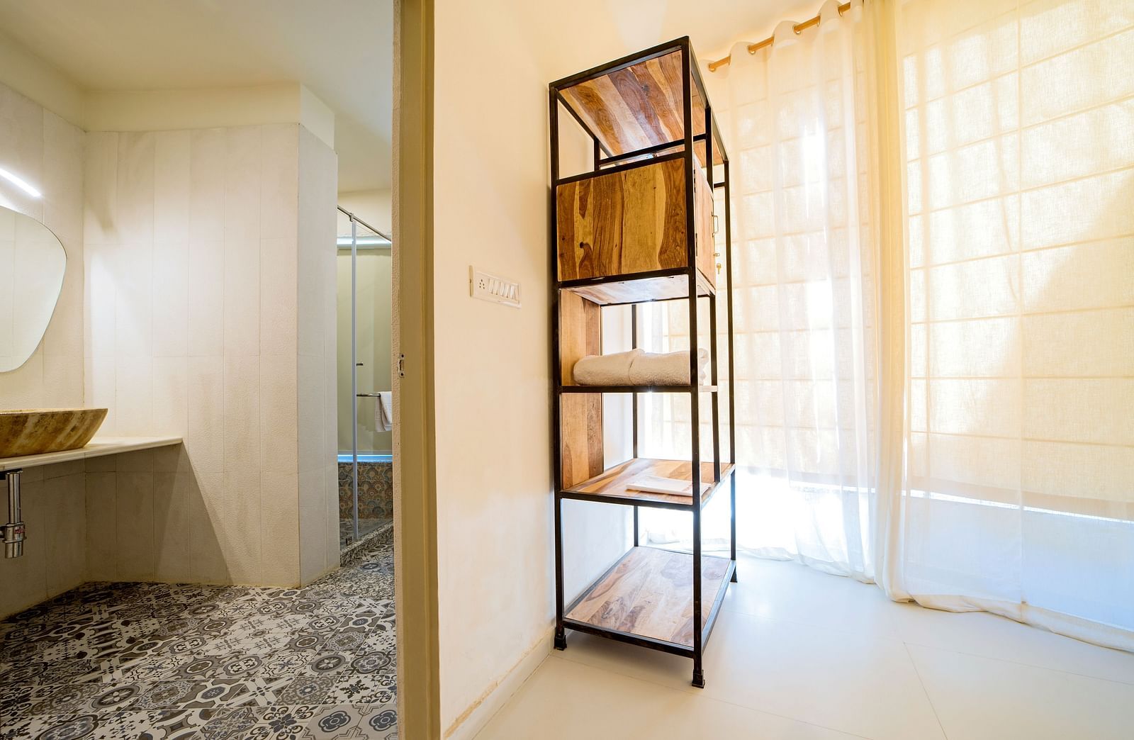 A room with a metal-framed wooden shelf and a washroom visible on the left with a sink and mirror at Valley by Grassfield. 