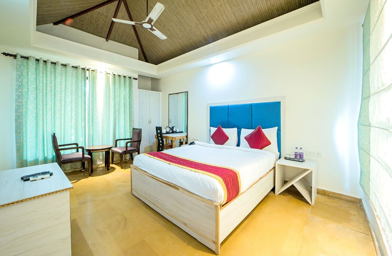 A room with a bed, a ceiling fan, and a seating area beside the window at Valley by Grassfield.