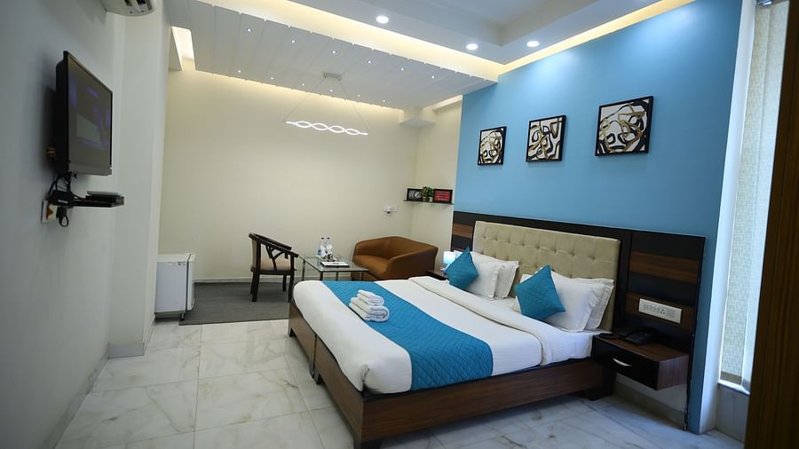 A room with two single beds featuring blue and white bedding, a television, and framed artwork on the wall - Asian Suites Cyber Park, Gurgaon