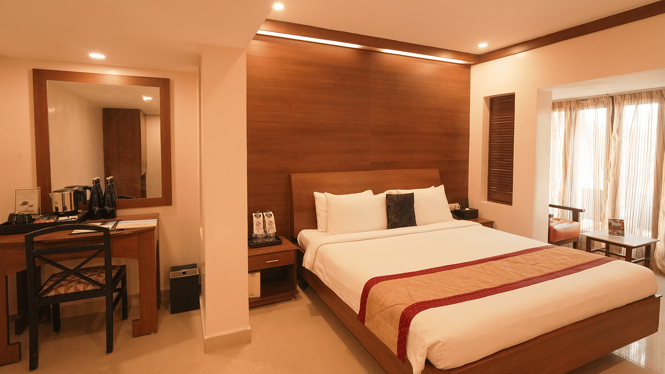 A room with a neatly arranged bed with good lighting and a desk and chair arranged in the side.