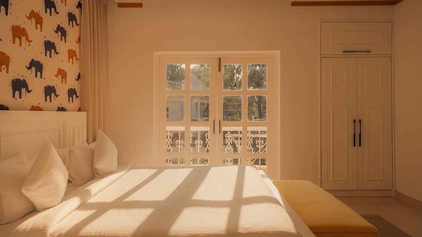 Cozy bedroom with warm lighting and elephant-themed wallpaper at Richmonde Ananta Elite, Goa.