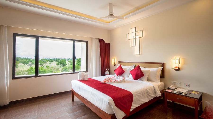 Honeymoon Suite with a plush king sized bed, bedside lamps, and a large window offering natural light and views