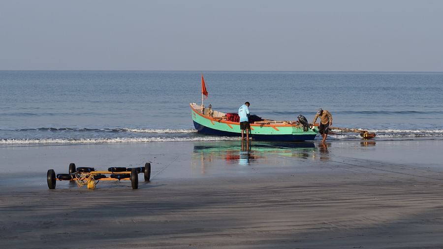 a man taking care of his boat on the beach in Dapoli