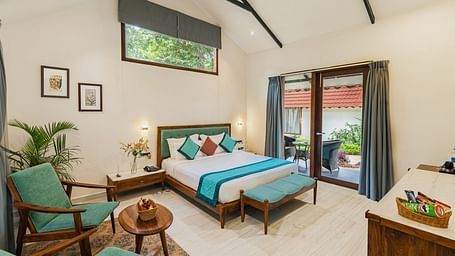 full view image from the corner of the luxury villa featuring a king size bed along with a full sized french windows at the far end of the room