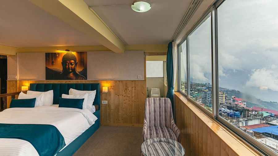 Suite with a king size bed, wall-mounted television, wooden table, and cosy lighting along with large window with city viewat Avianna Seven Seas, Darjeeling
