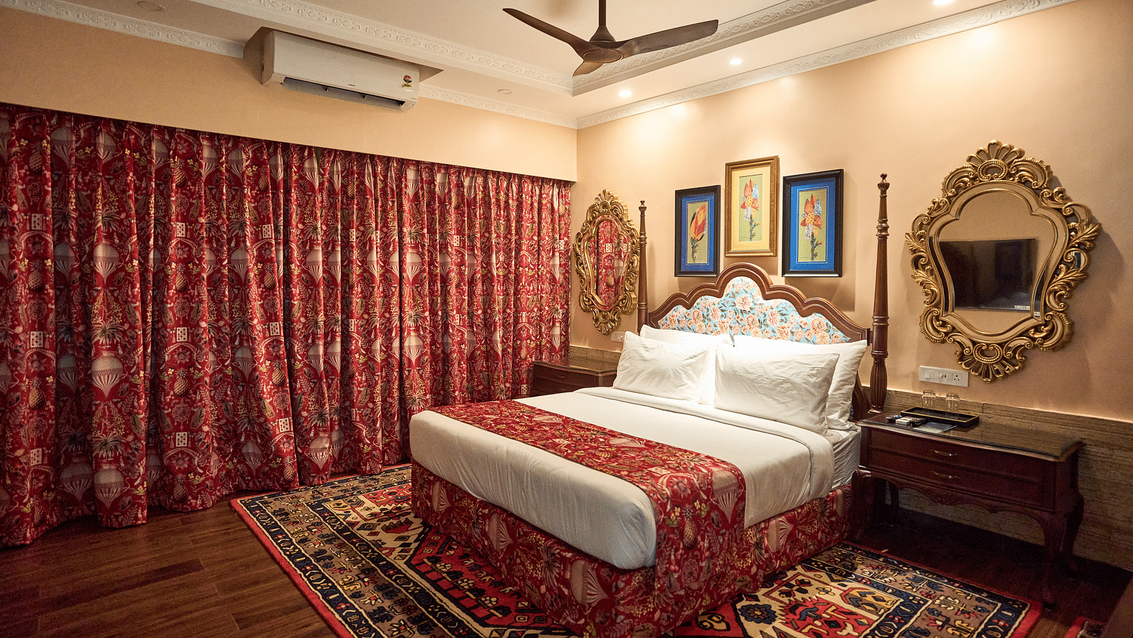 A spacious room featuring a large bed, wooden bedside tables, and windows draped with curtains at Mayfair Manor, Alibag