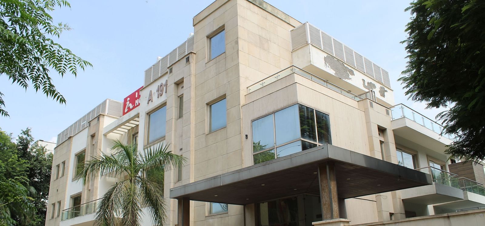 A facade image of Inde Hotels Vista Woods featuring a multi storey building surrounded by trees