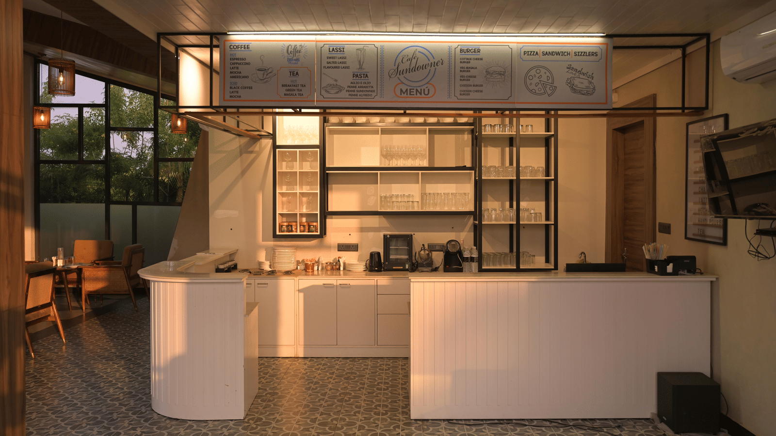 A modern cafe counter with clean lines, open shelving, and warm ambient lighting at Hotel Sonar Bangla Mayapur.