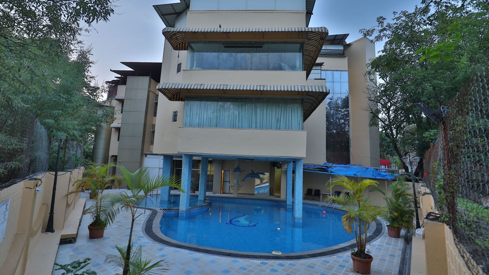 The exterior of a multi-story hotel building with a visible swimming pool in the foreground - Retreat Heritage, Lonavala
