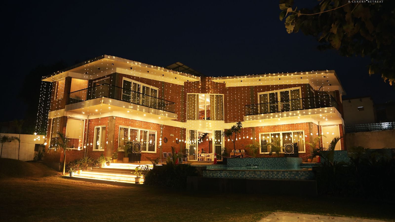 Exterior view of the building at night, showing lighting and plants at Tisya Farms, Gurgaon.