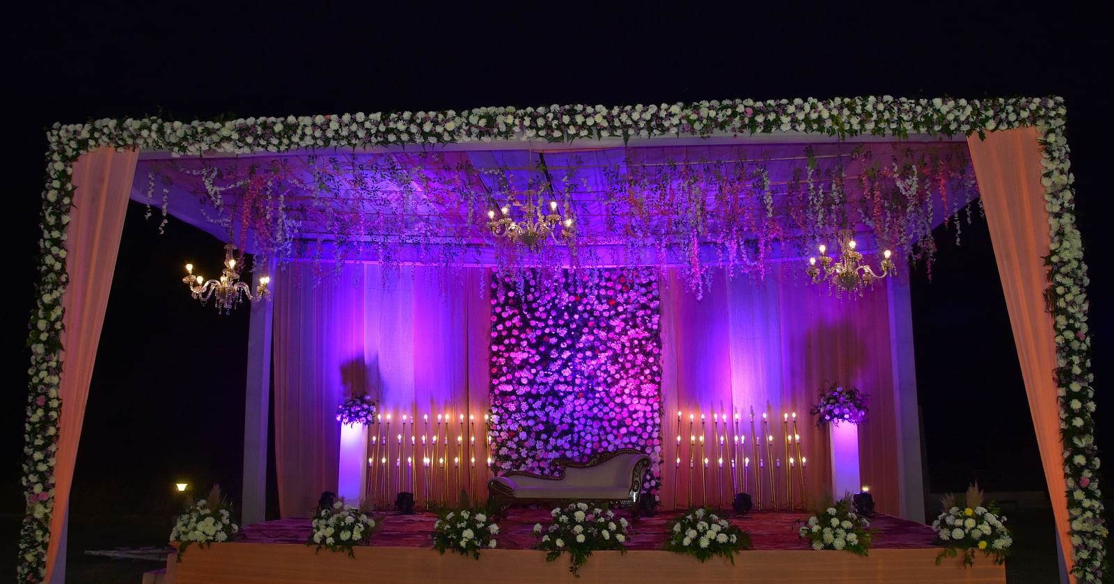 Nighttime wedding stage decor with purple lights at Vedikant Hotels & Resorts.