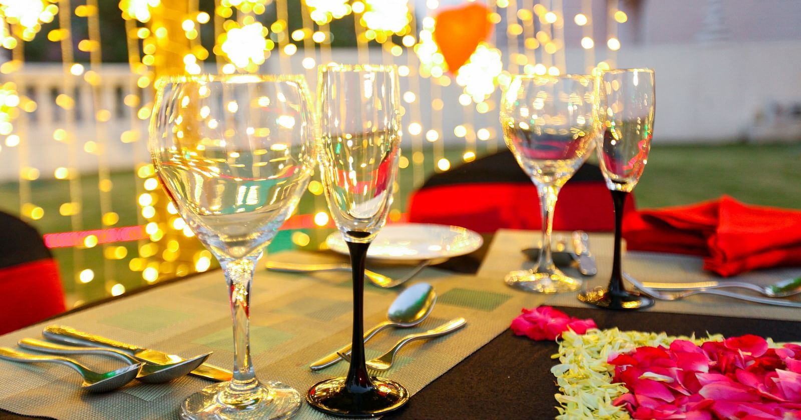 glasses set on a table with plates, cutlery and decoratations in the backdrop - Ramoji Film City Hotels in Hyderabad 