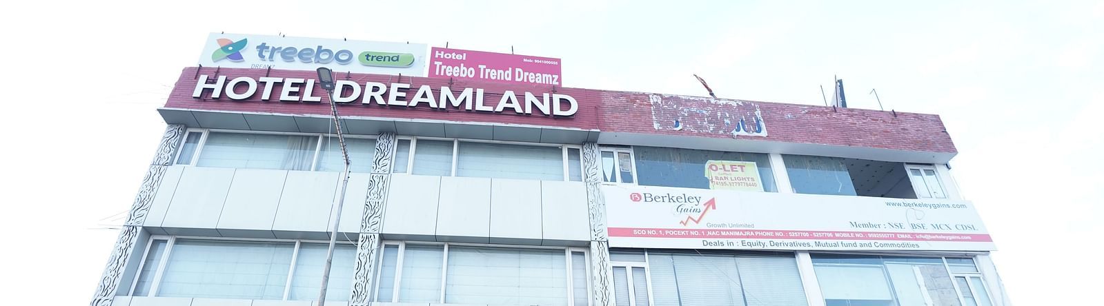 Facade image of Hotel Dreamland, Chandigarh with vehicles parked in the front.