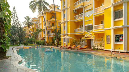 An image of an outdoor swimming pool framed by yellow buildings.