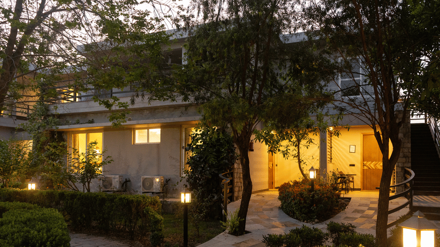 Building's exterior illuminated with warm lights, showing a pathway and garden area at The Golden Tusk, Jim Corbett
