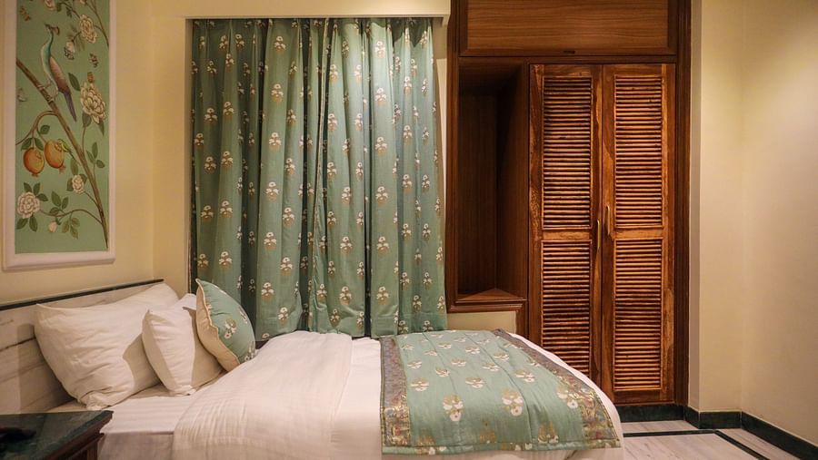 Side view of the Deluxe Twin Room featuring wooden storage and a spacious bed | Panna Vilas Udaipur