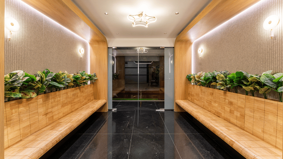 Stylish lobby corridor with wooden seating and indoor greenery at Rivido - Manyata