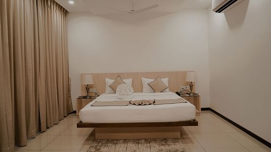 Pride Ranakpur Resort Convention Centre - interior view of the deluxe room featuring an air conditioner a fan and a queen size bed