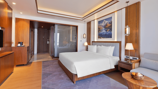 Modern Premium Double Room at Royal Tulip Shivapuri National Park - Kathmandu with wood furniture, a plush bed, and a sleek glass-partitioned bathroom.