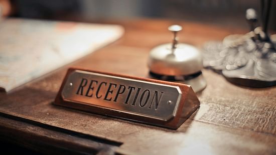 A close up shot of a reception desk with a reception sign and a small concierge bell