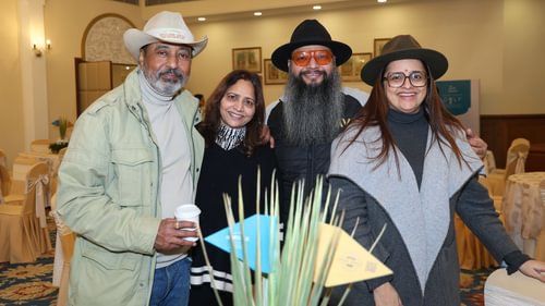 Two men and two women are standing together, one of the men holding a glass in his hand. - Heritage Village Resorts & Spa