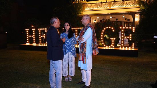 Two guests having a conversation in front of the glowing 'Heritage' signage during an evening event.