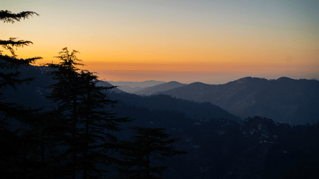 A sunset view over distant hills and trees near Perfectstayz Value Shimla (Namah Retreat).