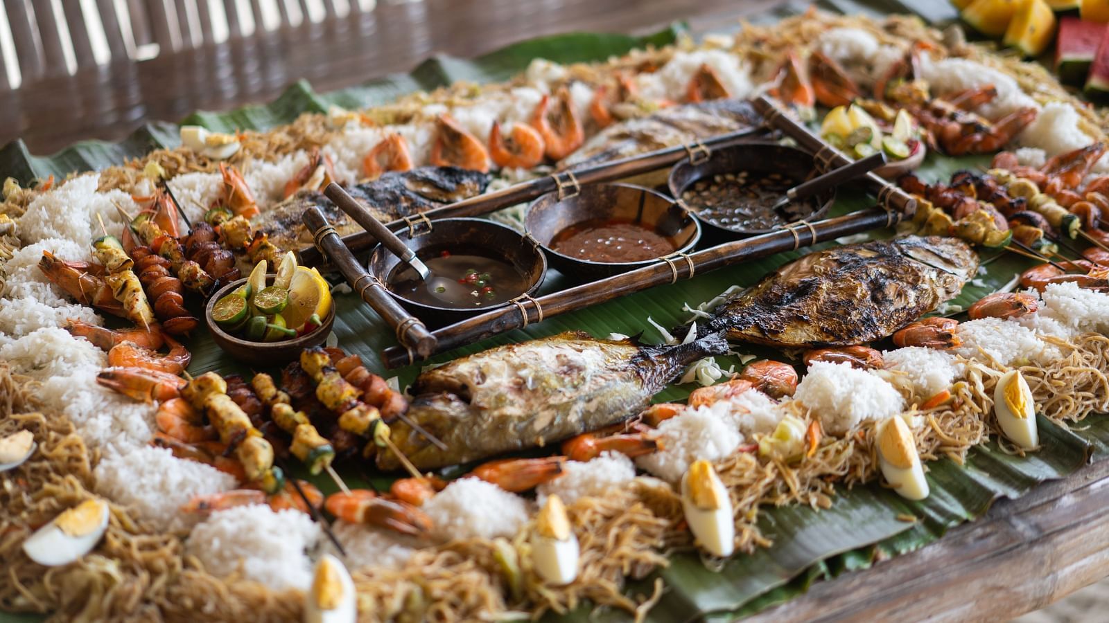 Tabletop grilled seafood and vegetable feast with shells and skewers at Flower Island Resort.