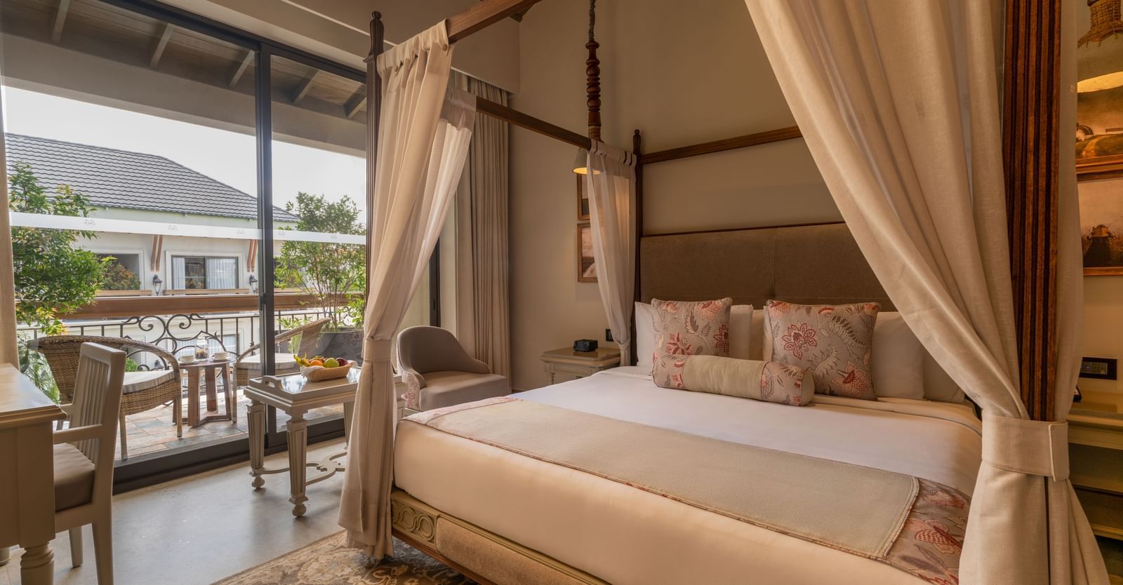 A plush double bed in the Premium Room at The Evren, Vagator, with a balcony beside it featuring a sit-out area.