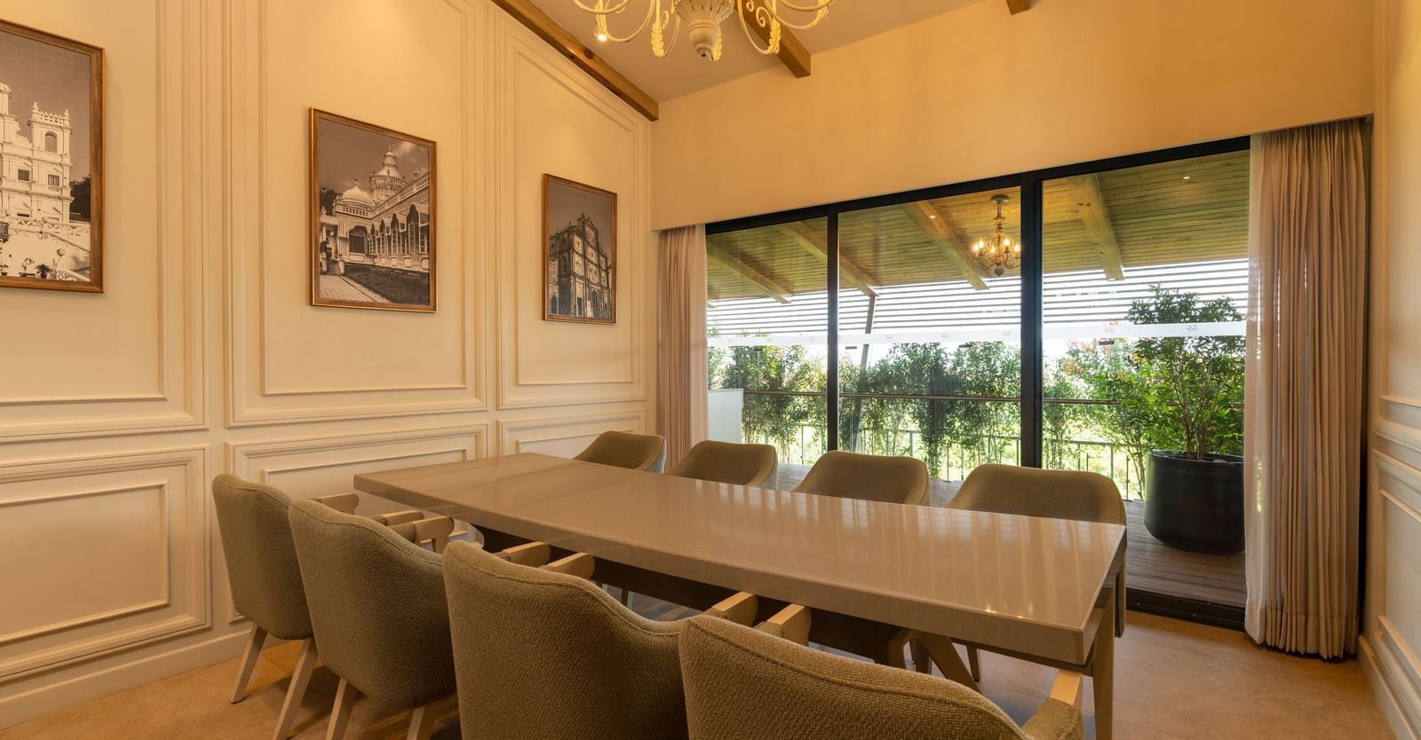 A brightly-lit boardroom at The Evren, Vagator, featuring a long conference table with a window behind it overlooking the lush green lawns.