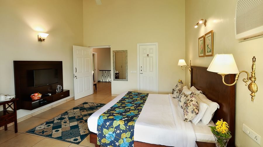 An elegant room with pristine white bed and delicate interiors, captured from a lower angle showing room amenities like  television, bedside lamp and more - Lamrin Norwood Green, Palampur