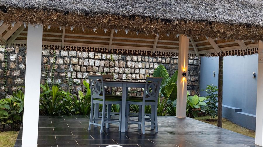 image of the outdoor seating area with wooden chairs and a table under the gazebo - Darza Resorts