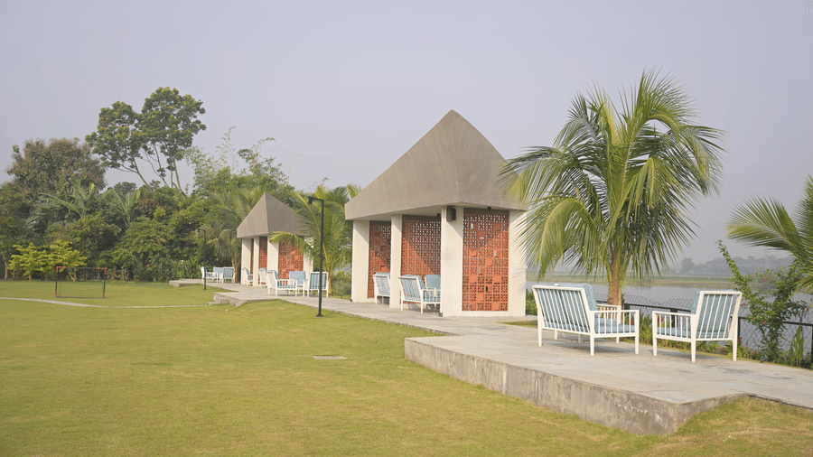 Small gazebo-style structure surrounded by open lawns and palm trees at Hotel Sonar Bangla Mayapur.