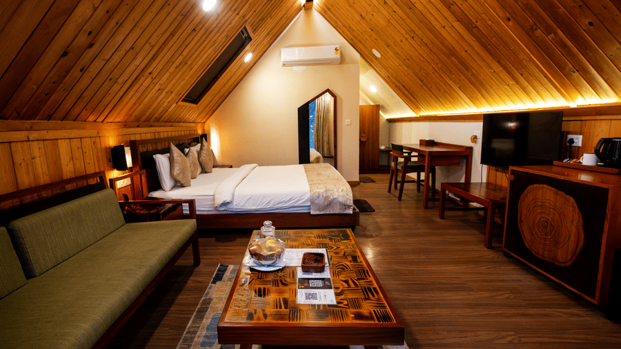 Side-angle view of a bedroom with a large bed, conical ceiling, television, and furniture at Hotel Sonar Bangla, Taki.