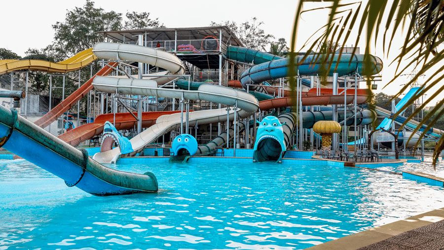 Water park pool with a complex of water slides and tunnels in the background, with people enjoying the water at Kumar Resort by Turtle.