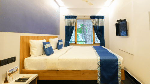A large bed next to a large window in the villa at MGM Whispering Nest, Yelagiri.