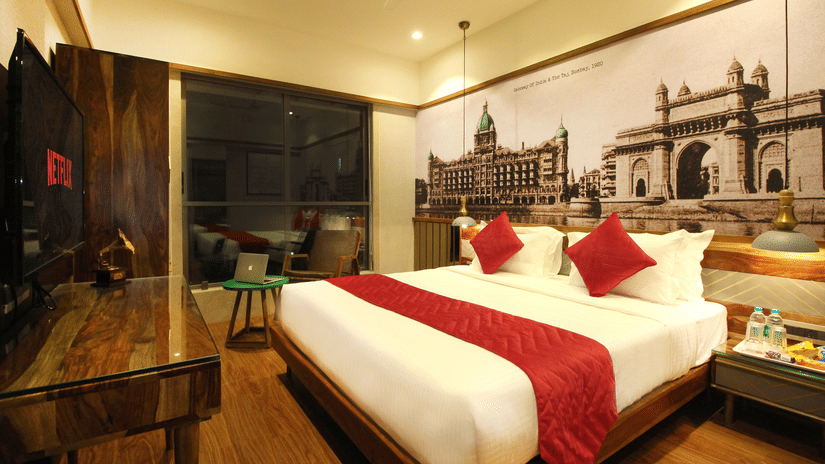 An overview of the 2 Bedroom Suite with a double bed, side tables, a tv, an expansive window overlooking the city in Khar area.